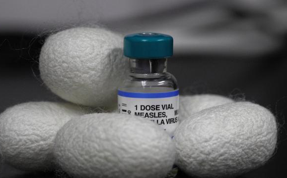 Photo of a vaccine vial nestled in a pile of silk cacoons